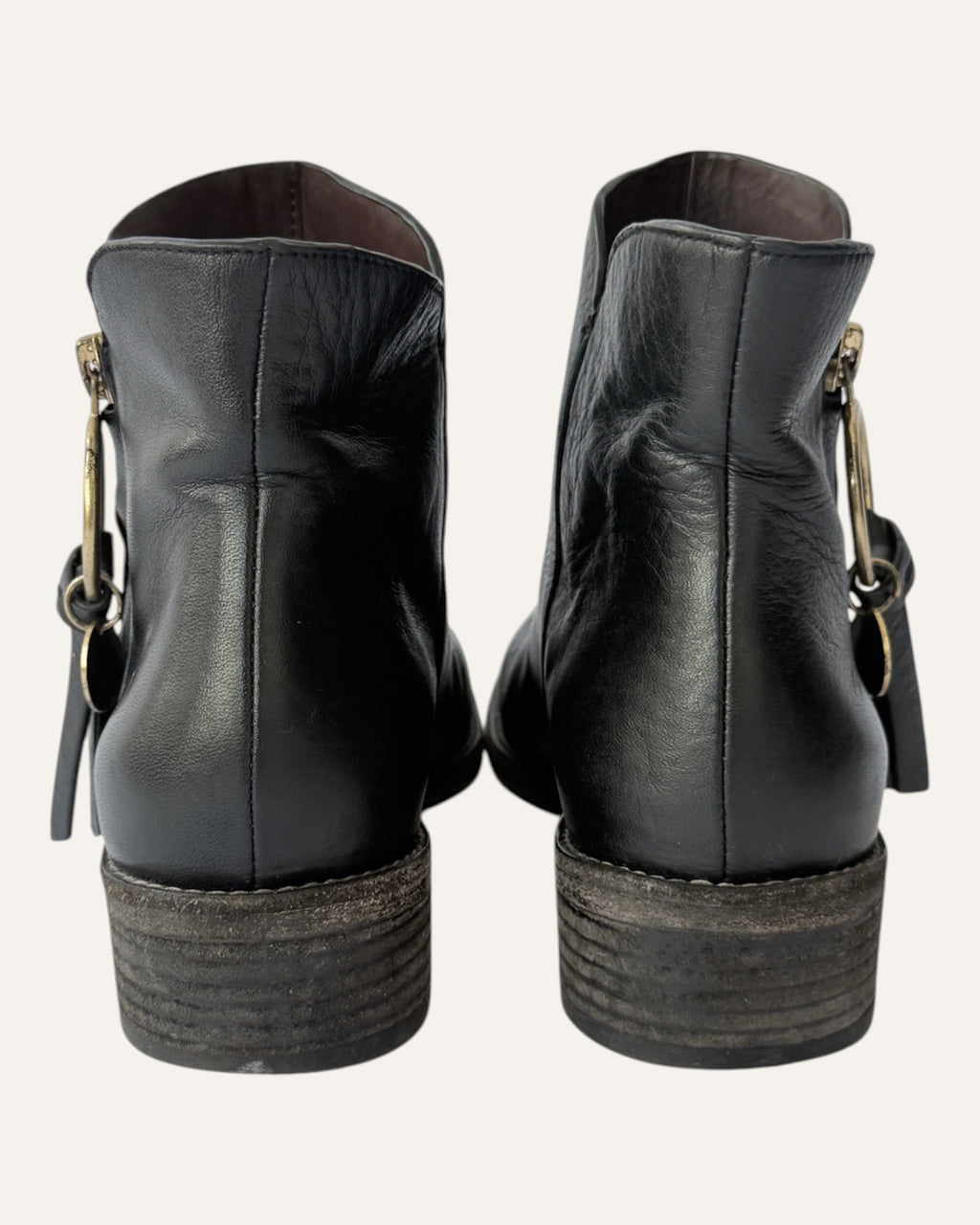 See by Chloé black leather moto ankle boot with gold ring zip pull, logo charm, and stacked heel