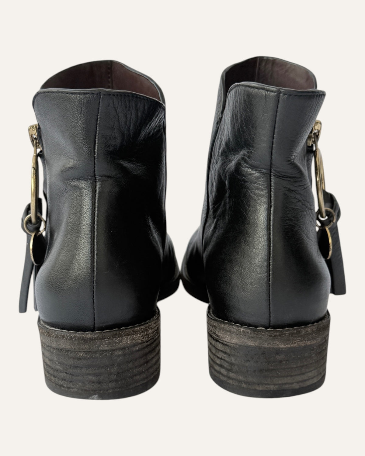 See by Chloé black leather moto ankle boot with gold ring zip pull, logo charm, and stacked heel