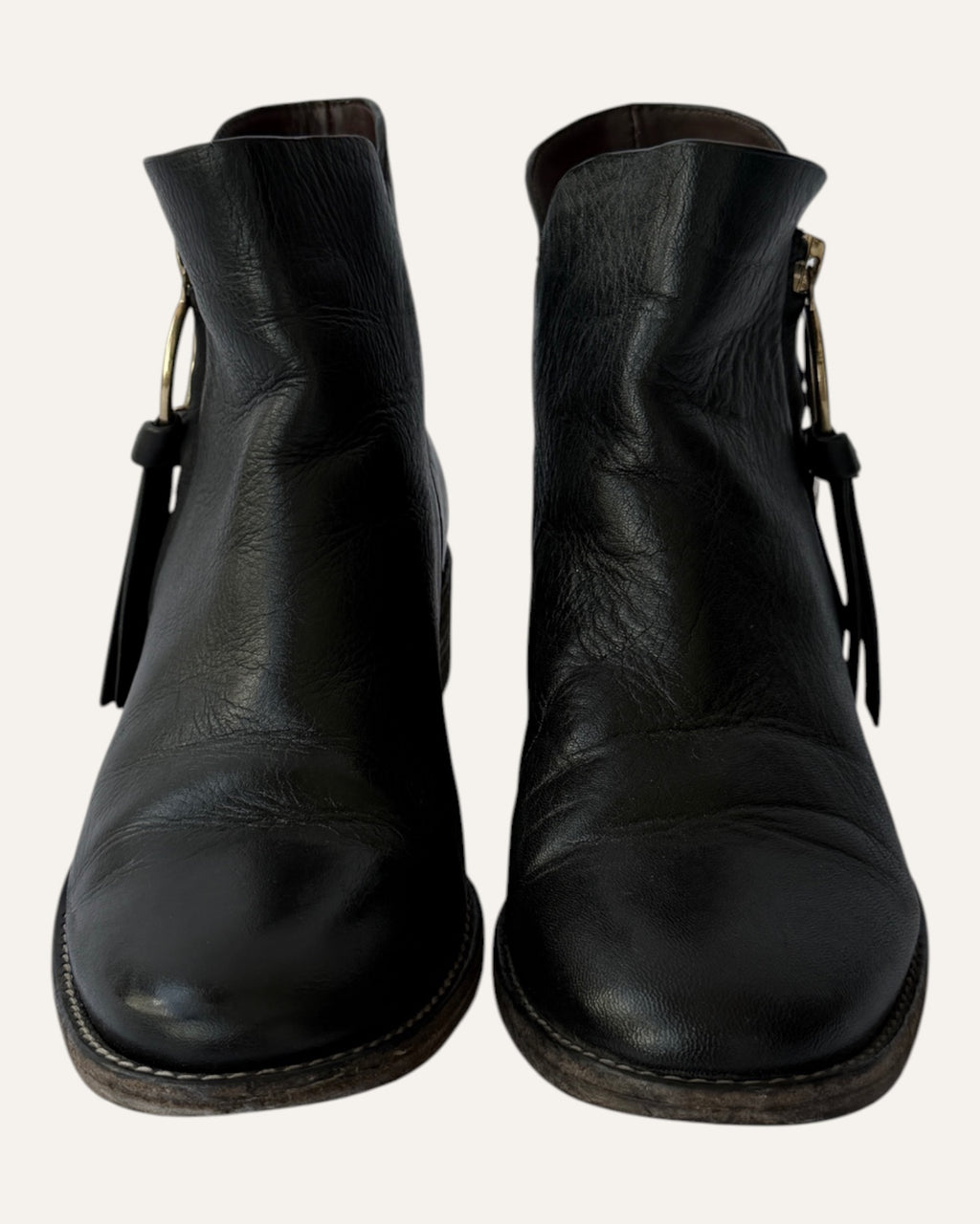 See by Chloé black leather moto ankle boot with gold ring zip pull, logo charm, and stacked heel