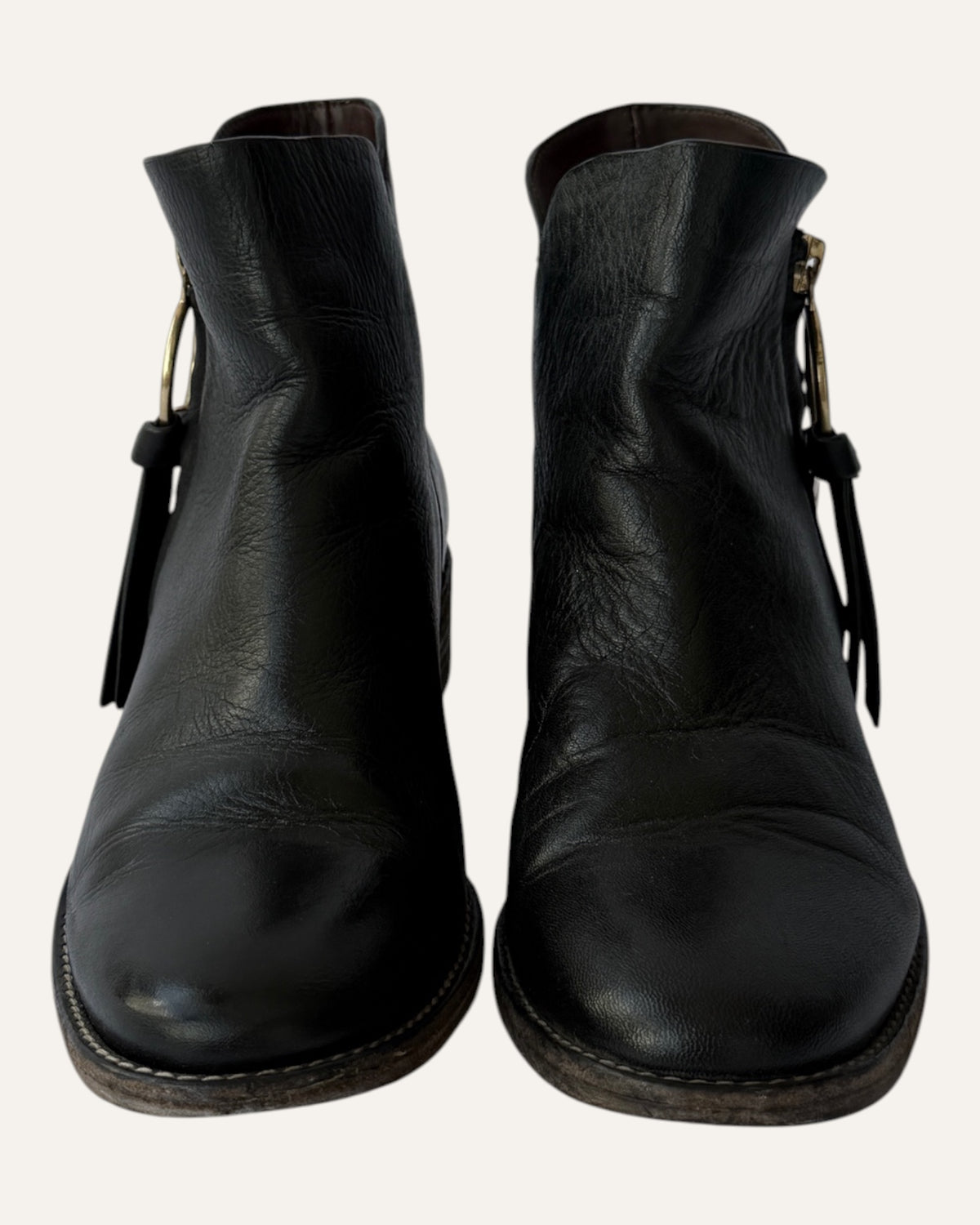 See by Chloé black leather moto ankle boot with gold ring zip pull, logo charm, and stacked heel