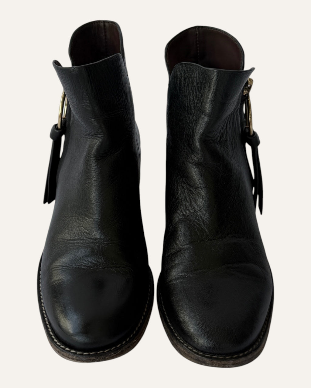See by Chloé black leather moto ankle boot with gold ring zip pull, logo charm, and stacked heel