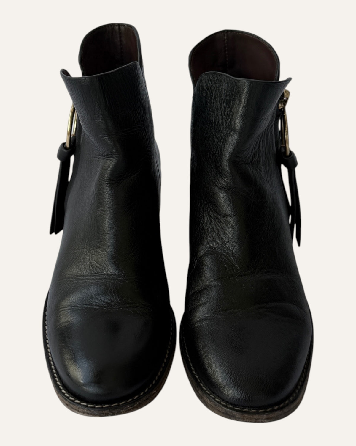 See by Chloé black leather moto ankle boot with gold ring zip pull, logo charm, and stacked heel