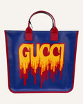 Gucci melting logo tote in royal blue coated canvas with red leather handles and yellow dripping logo print